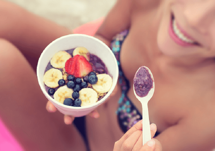 Žena raňajkuje jogurt s ovocím